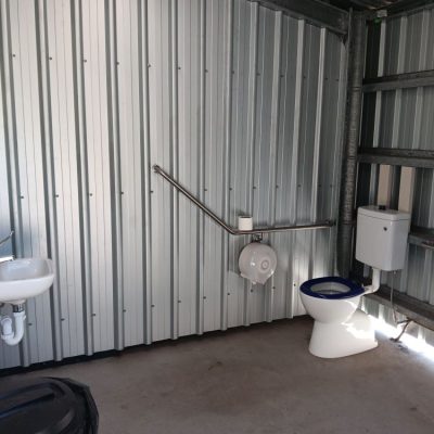Accessible toilet with handrail and handbasin